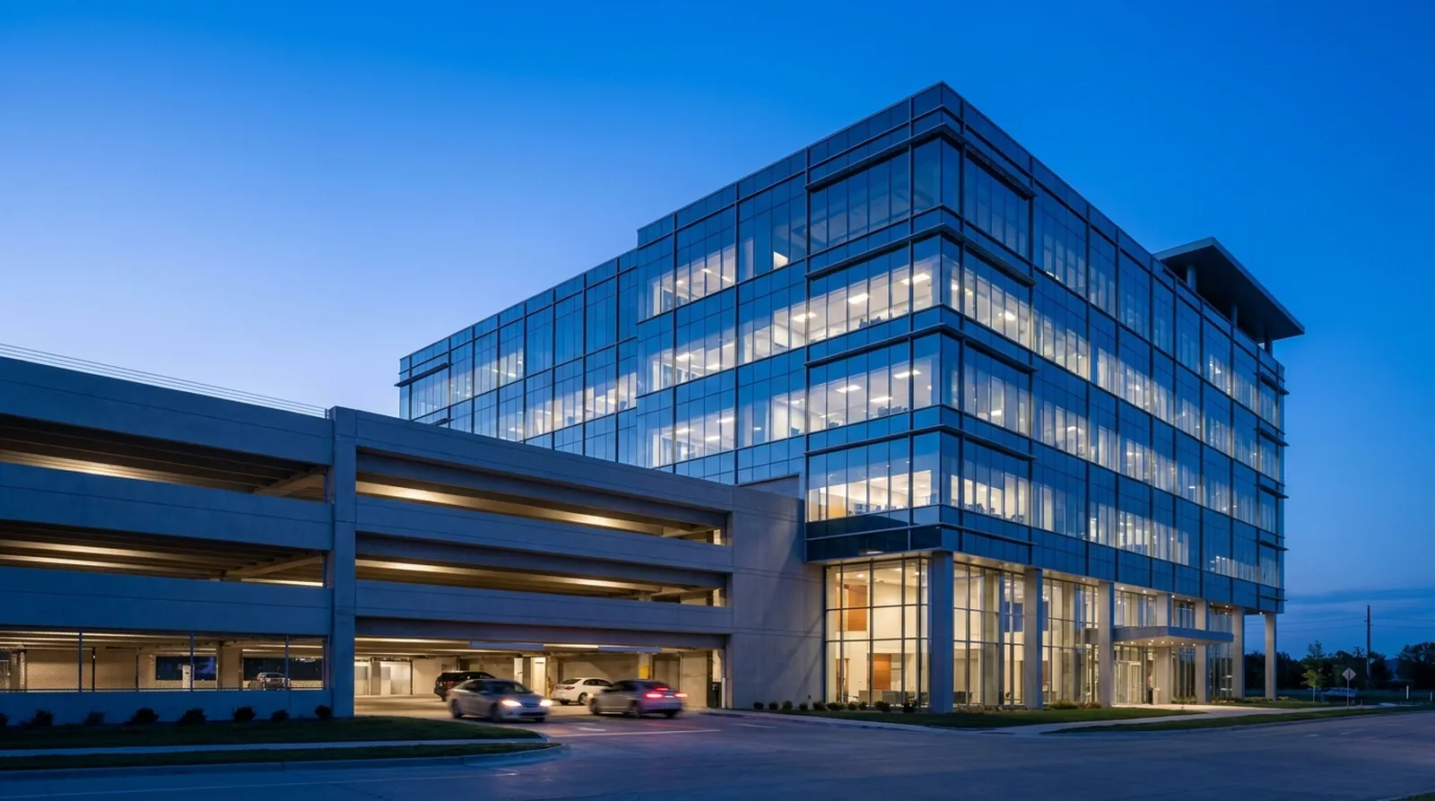 Glass office building with an attached parking structure at twilight